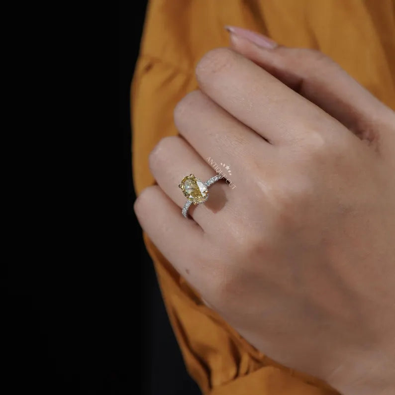 Hand wearing a ring with a yellow gemstone against an orange background