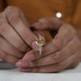 Close-up of hands holding a yellow diamond ring with a blurred background

