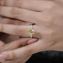 Close-up of a hand wearing a yellow diamond ring with a blurred background

