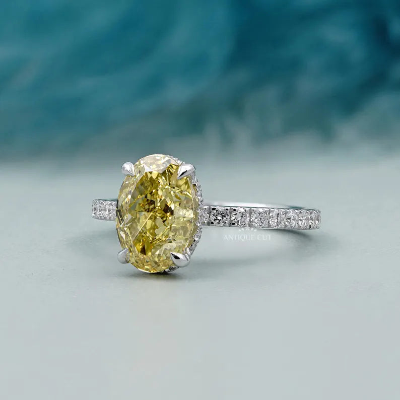 Ring with a yellow diamond and smaller diamonds on a light blue background