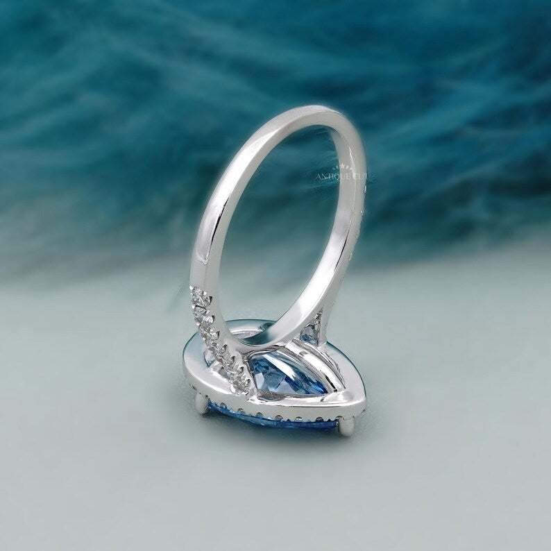 Pear shape blue diamond ring with halo and pave band