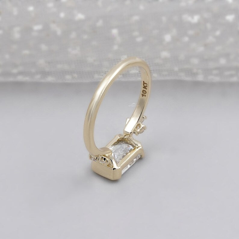 Contemporary emerald cut diamond ring in horizontal bezel yellow gold