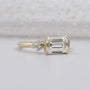 East west emerald diamond ring with sleek half bezel yellow gold band