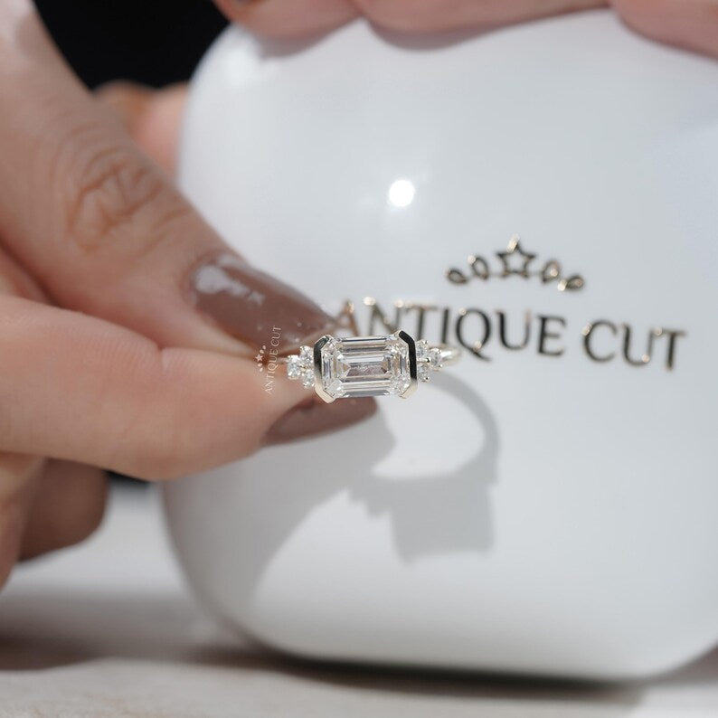 Elegant east west emerald diamond ring with sculptural half bezel
