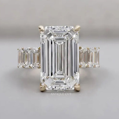 Emerald cut diamond engagement ring with tapered side stones in yellow gold
