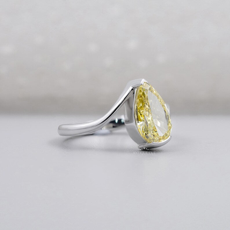 Side view of pear shaped yellow diamond bypass ring