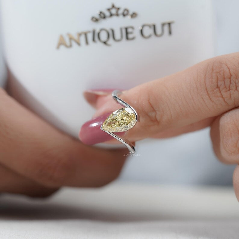 Detailed shot of pear shaped yellow diamond and prong setting