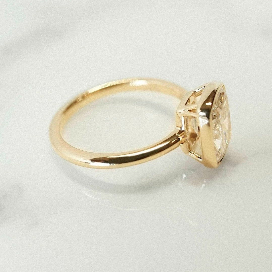 Yellow gold bezel set diamond ring with cushion cut center