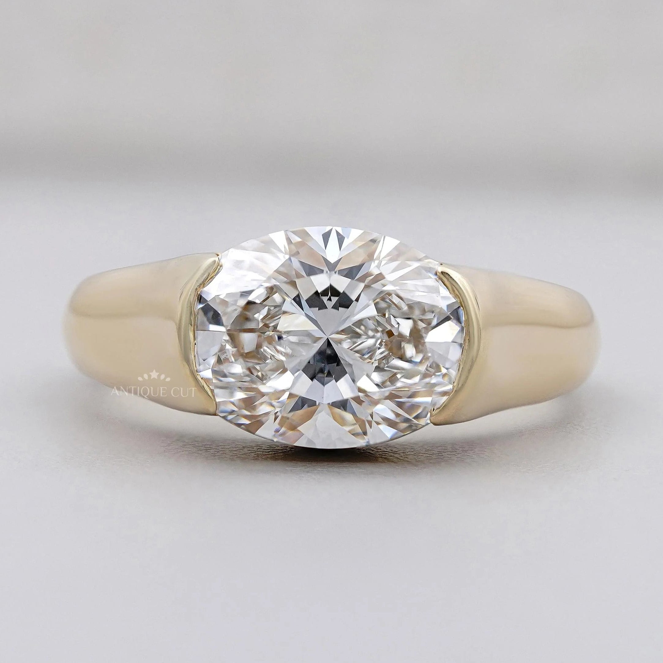 East-west oval cut diamond ring with half bezel setting in yellow gold
