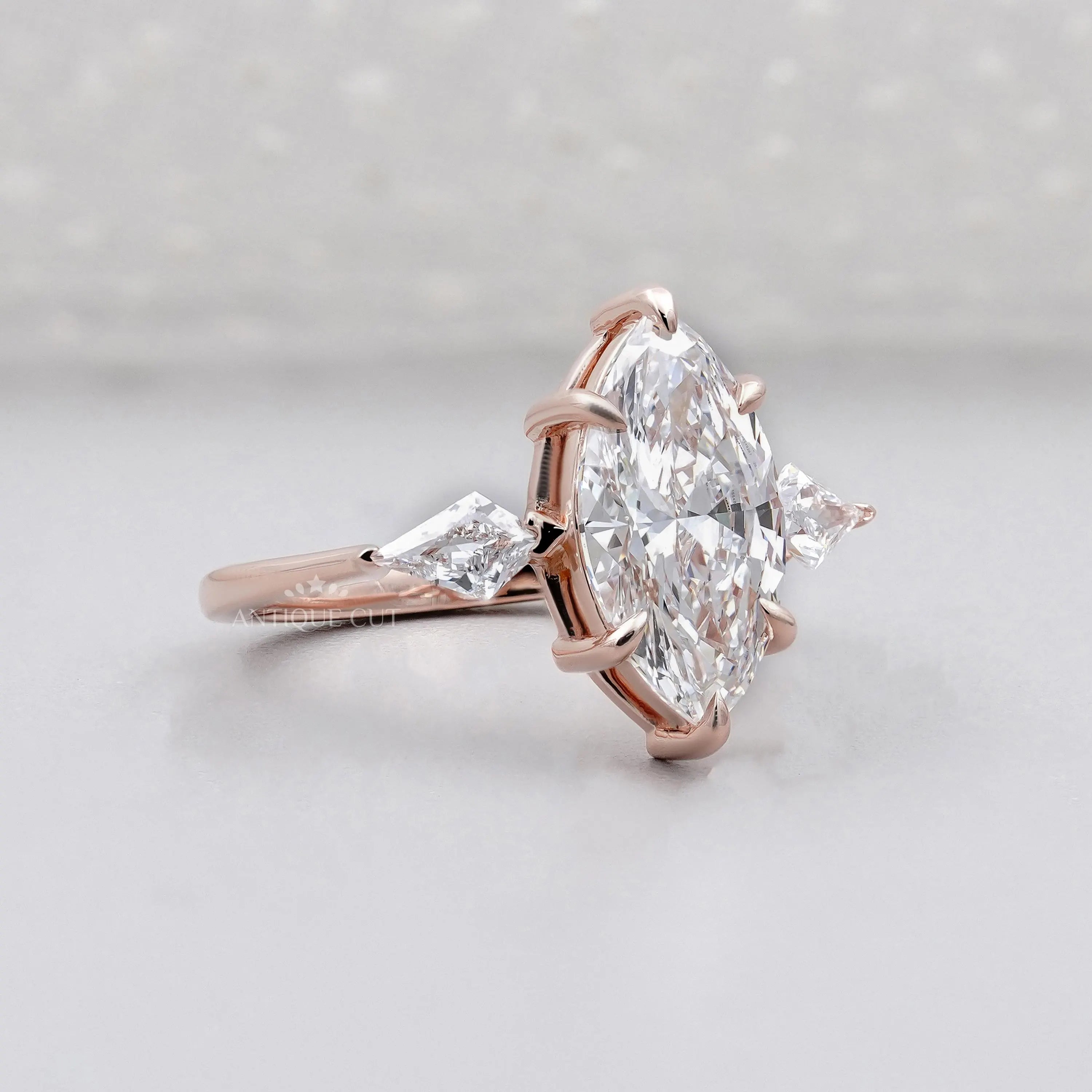 Rose gold ring with a large marquise-shaped diamond on a light gray background


