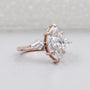 Rose gold ring with a large marquise-shaped diamond on a light gray background

