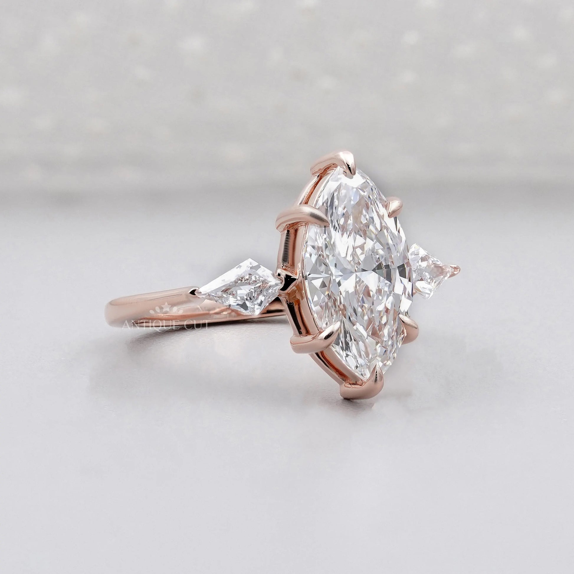 Rose gold ring with a large marquise-shaped diamond on a light gray background

