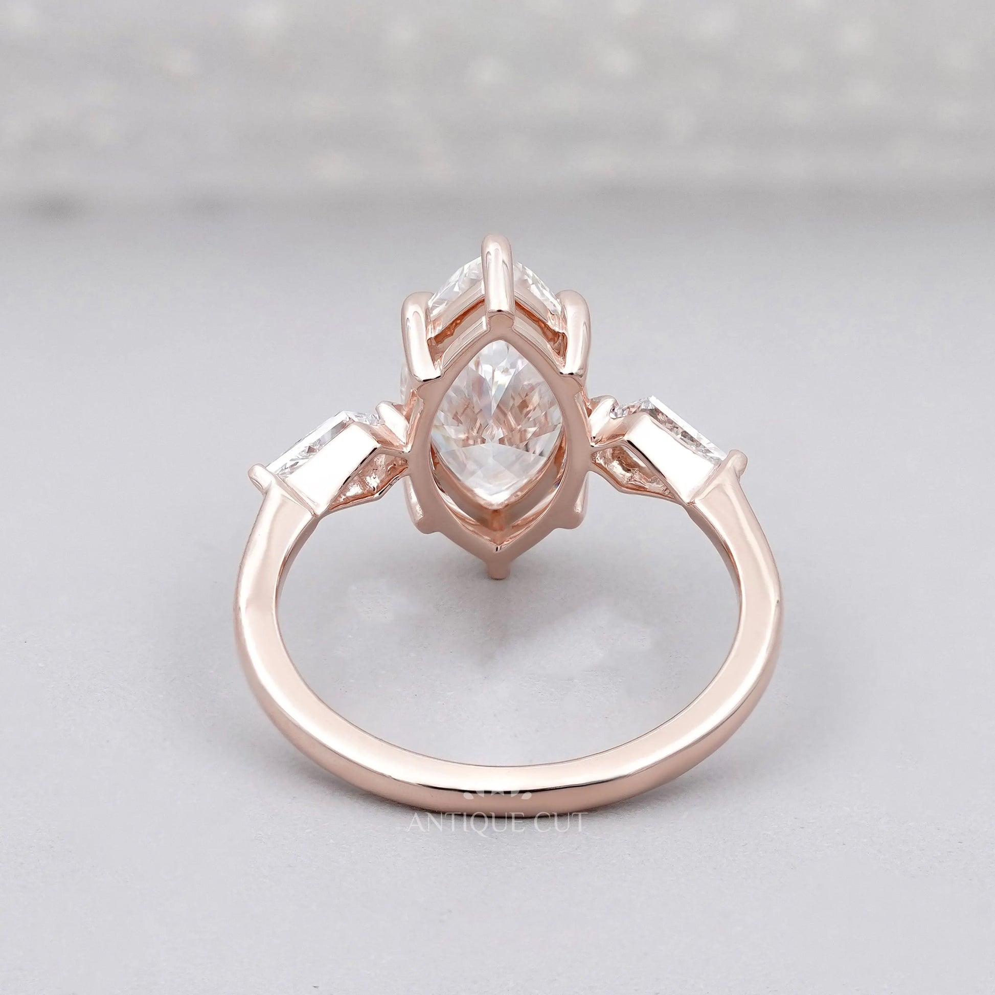 Rose gold ring with a pear-shaped diamond on a light gray background

