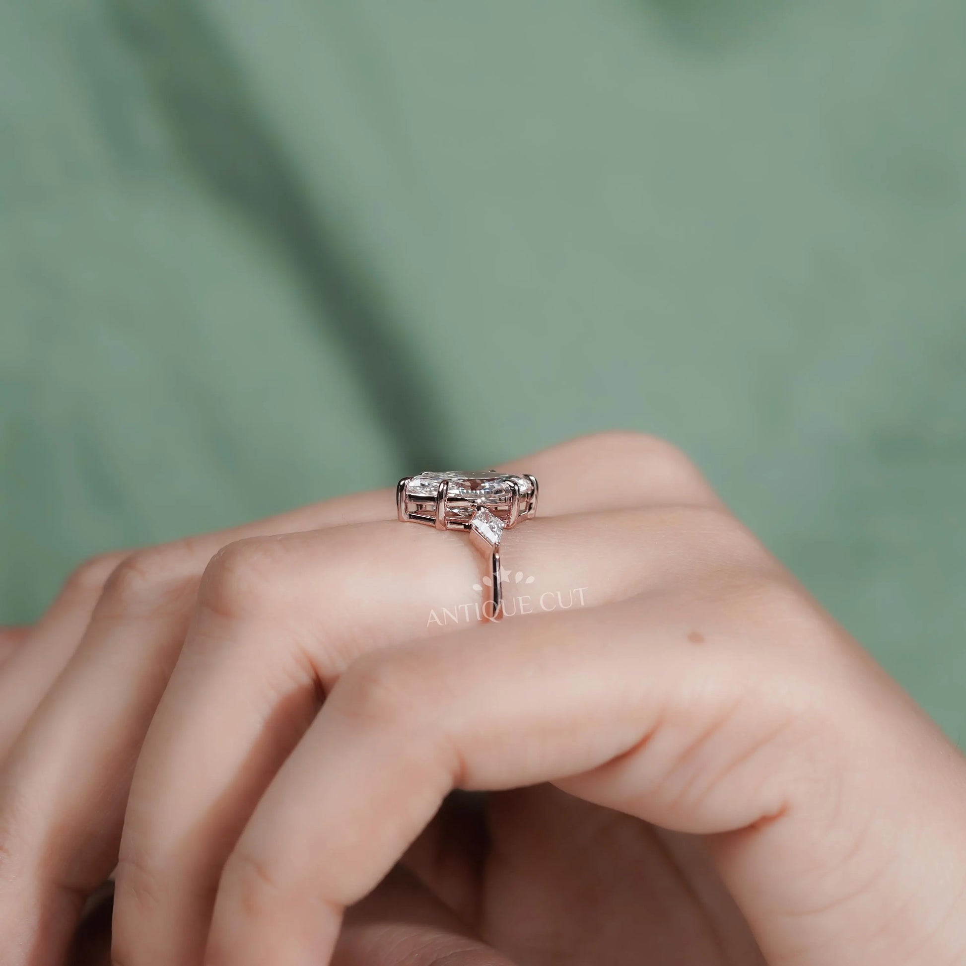Rose gold ring with a diamond on a hand against a green background

