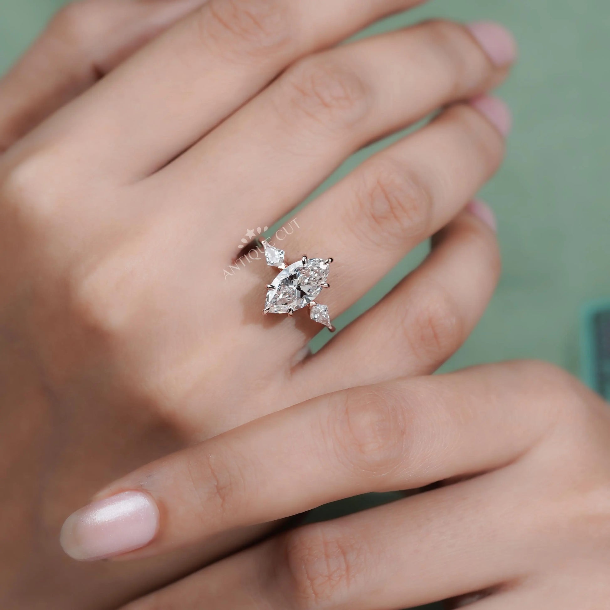 Close-up of a hand wearing a diamond ring with a blurred green background

