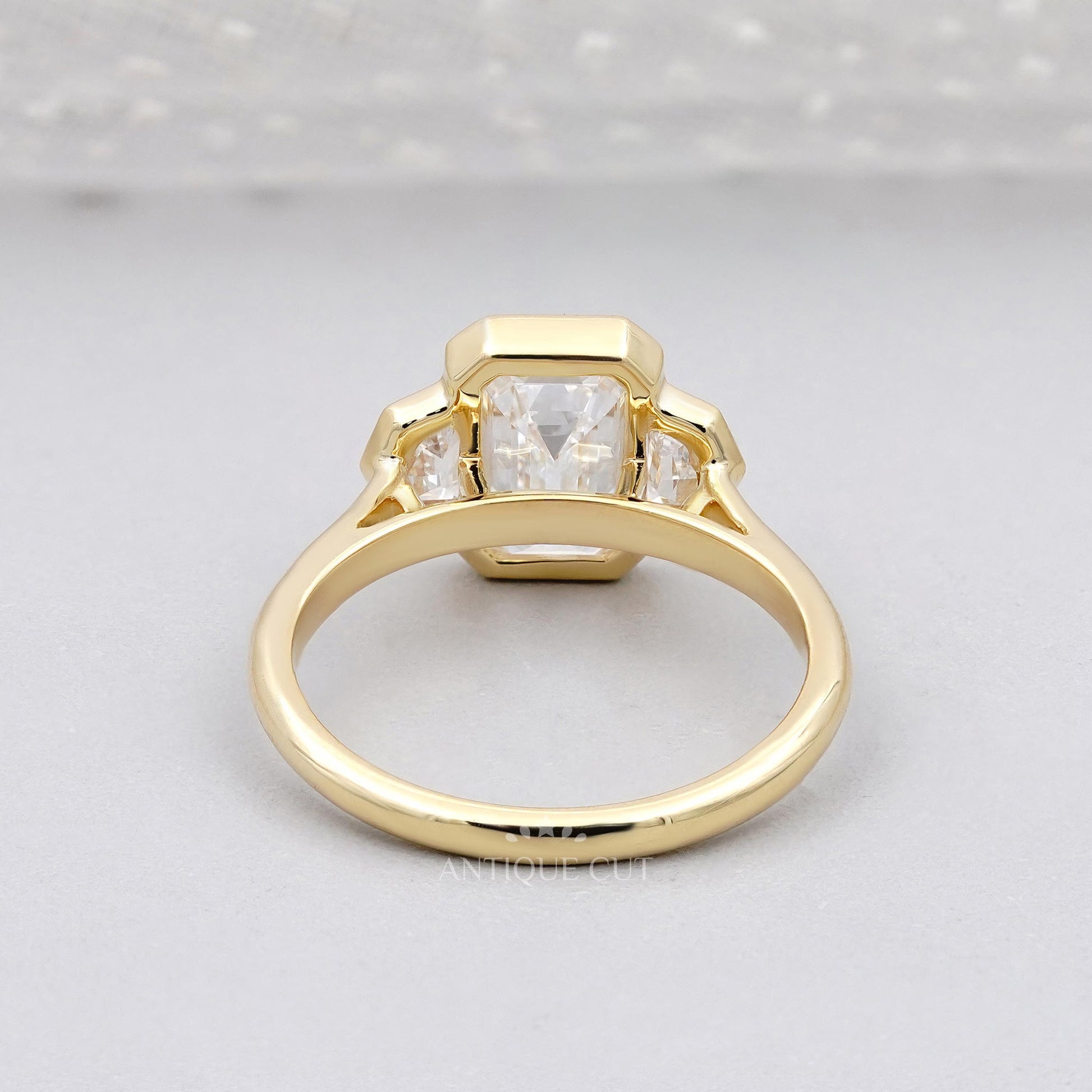 Gold ring with three diamonds on a light gray background

