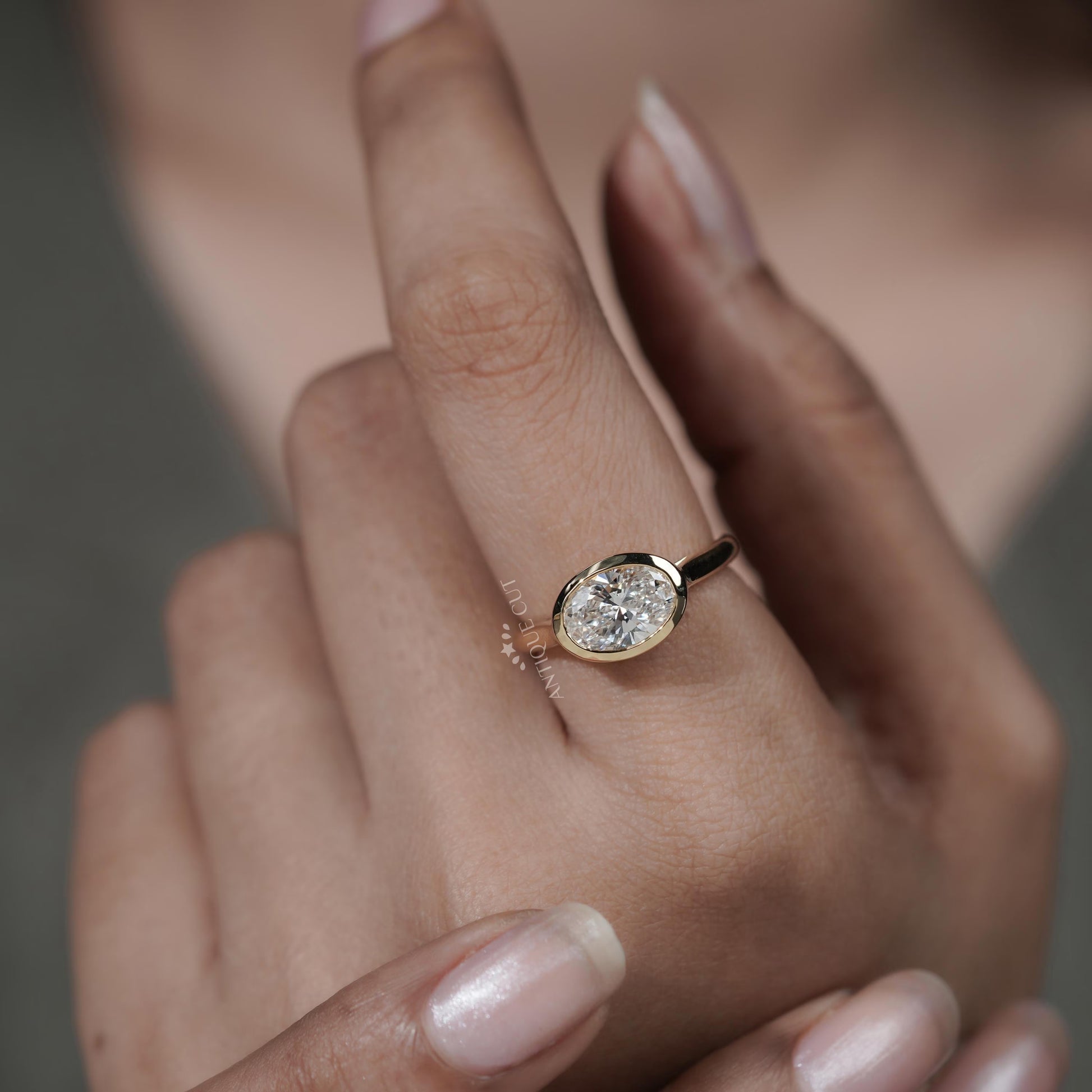 Gold ring with a diamond on a person's finger against a blurred background

