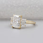 Gold ring with three diamond stones on a light gray background


