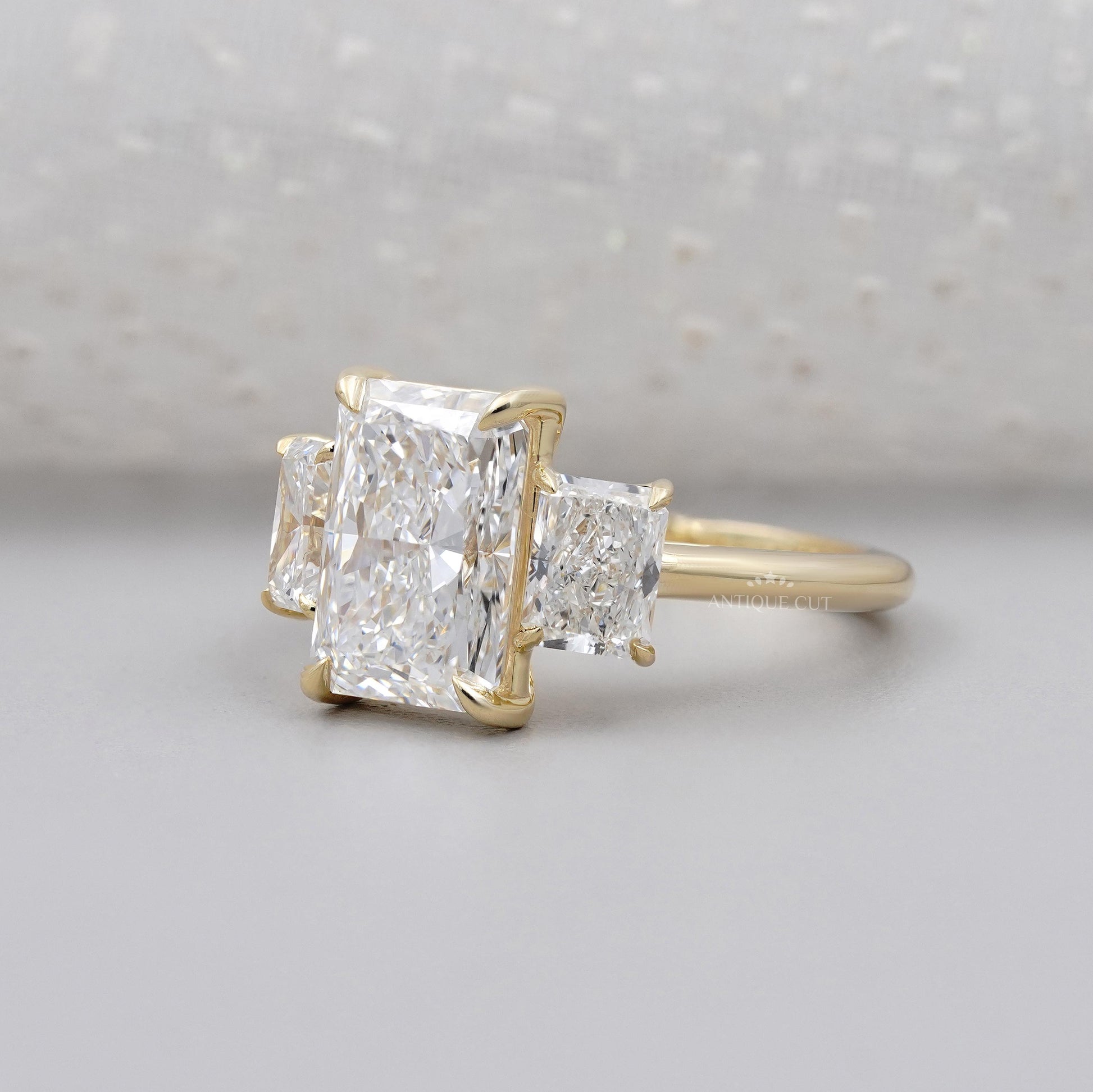 Gold ring with three diamond stones on a light gray background

