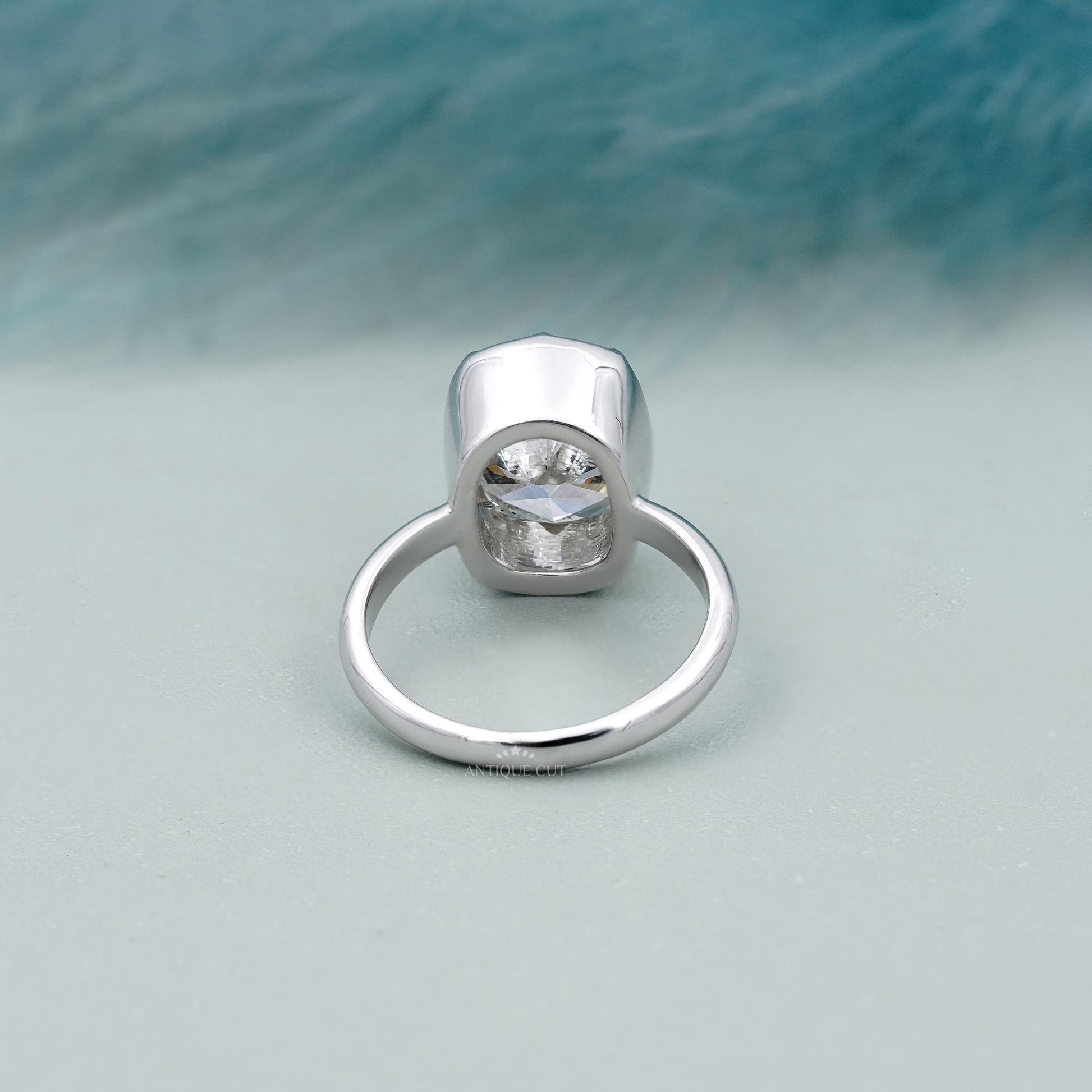 Silver ring with a diamond on a light blue background

