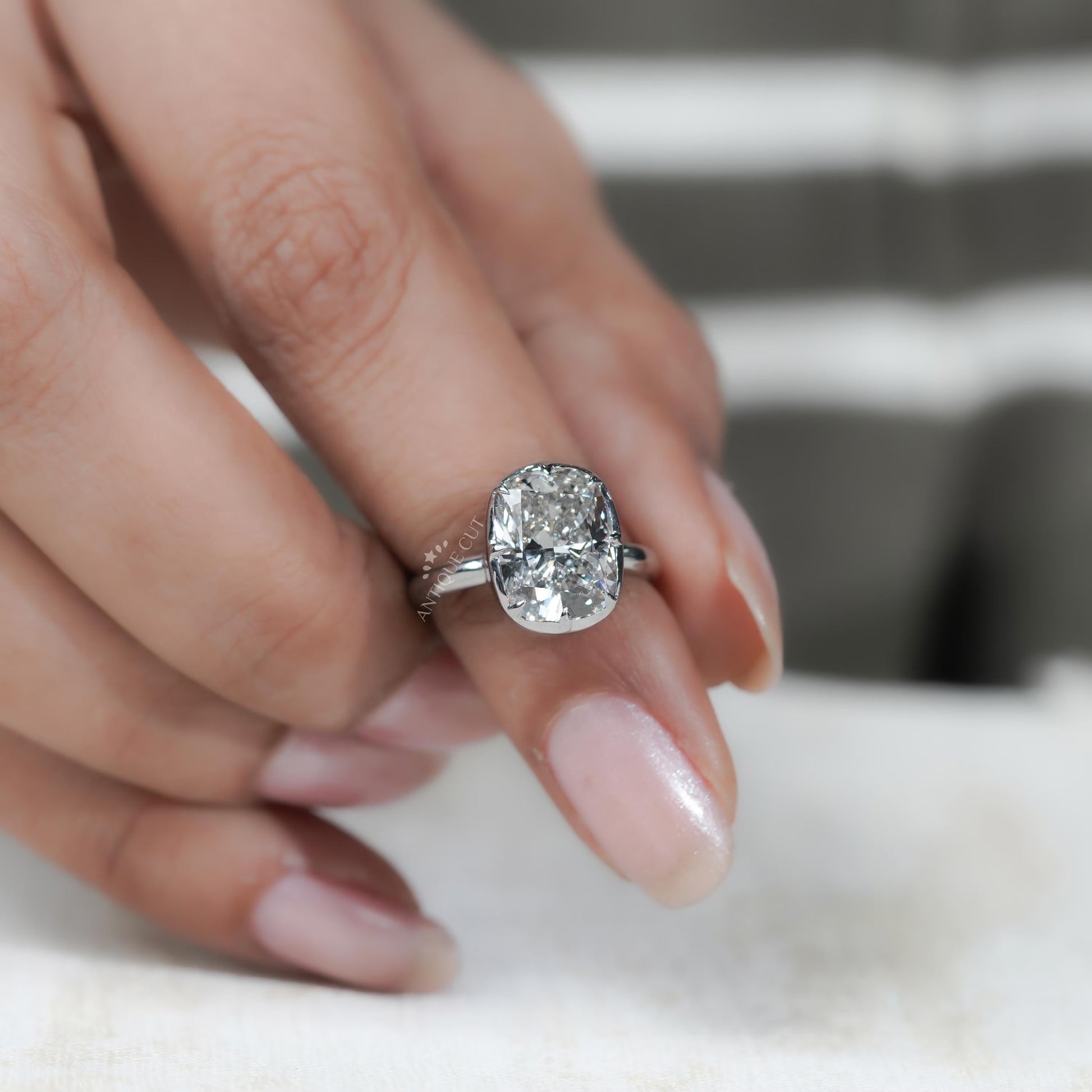Close-up of a hand wearing a diamond ring with a blurred background


