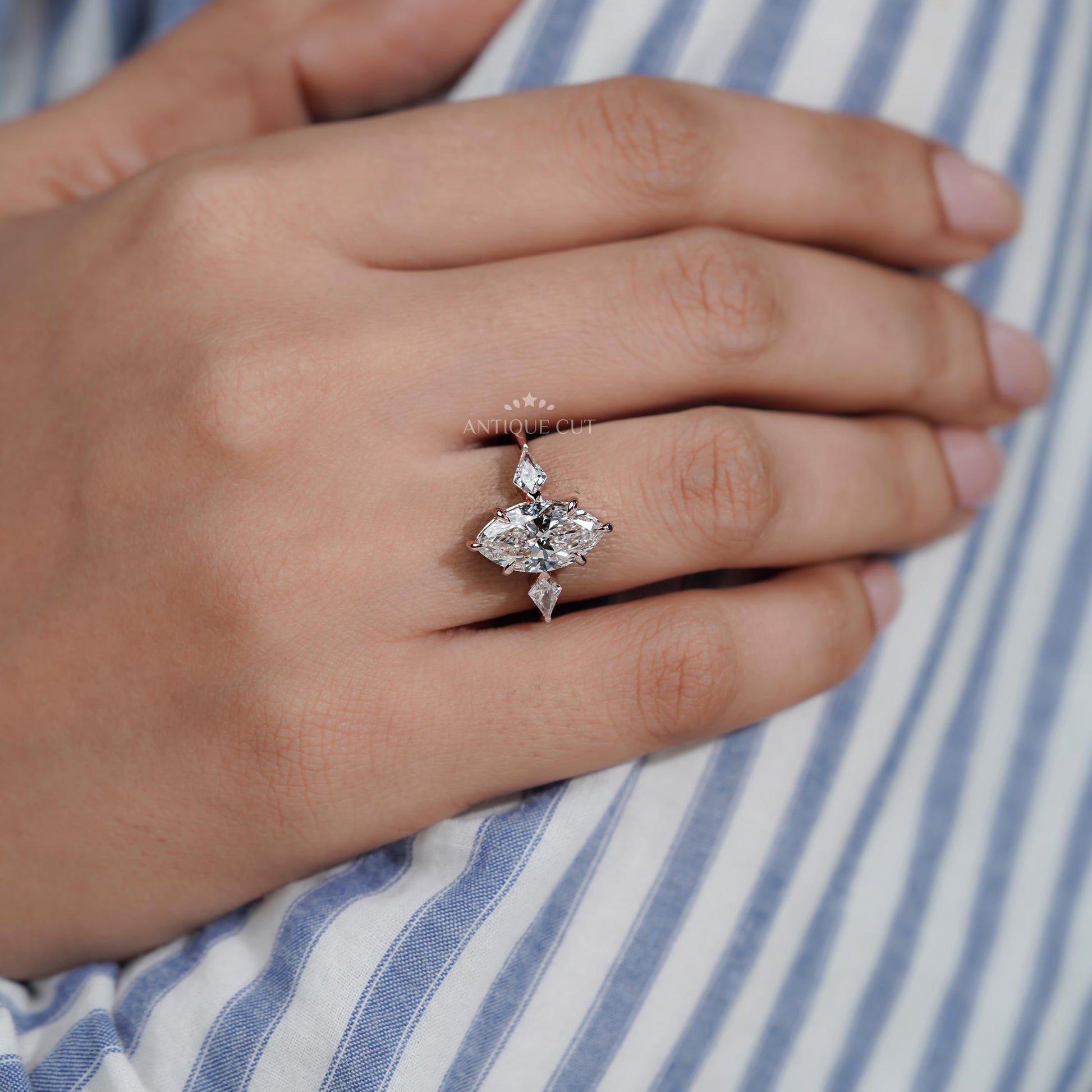 Close-up of a hand wearing a diamond ring on a striped fabric background

