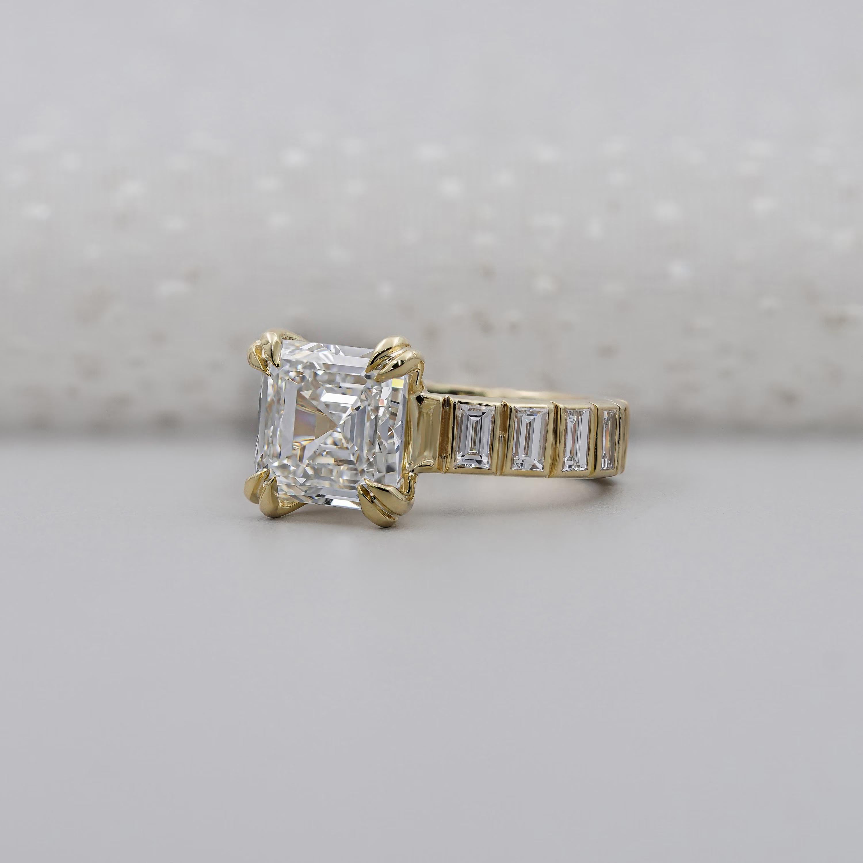 Gold ring with a large diamond and smaller baguette diamonds on a light gray background

