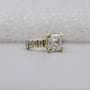 Gold ring with a large diamond and smaller baguette diamonds on a light gray background

