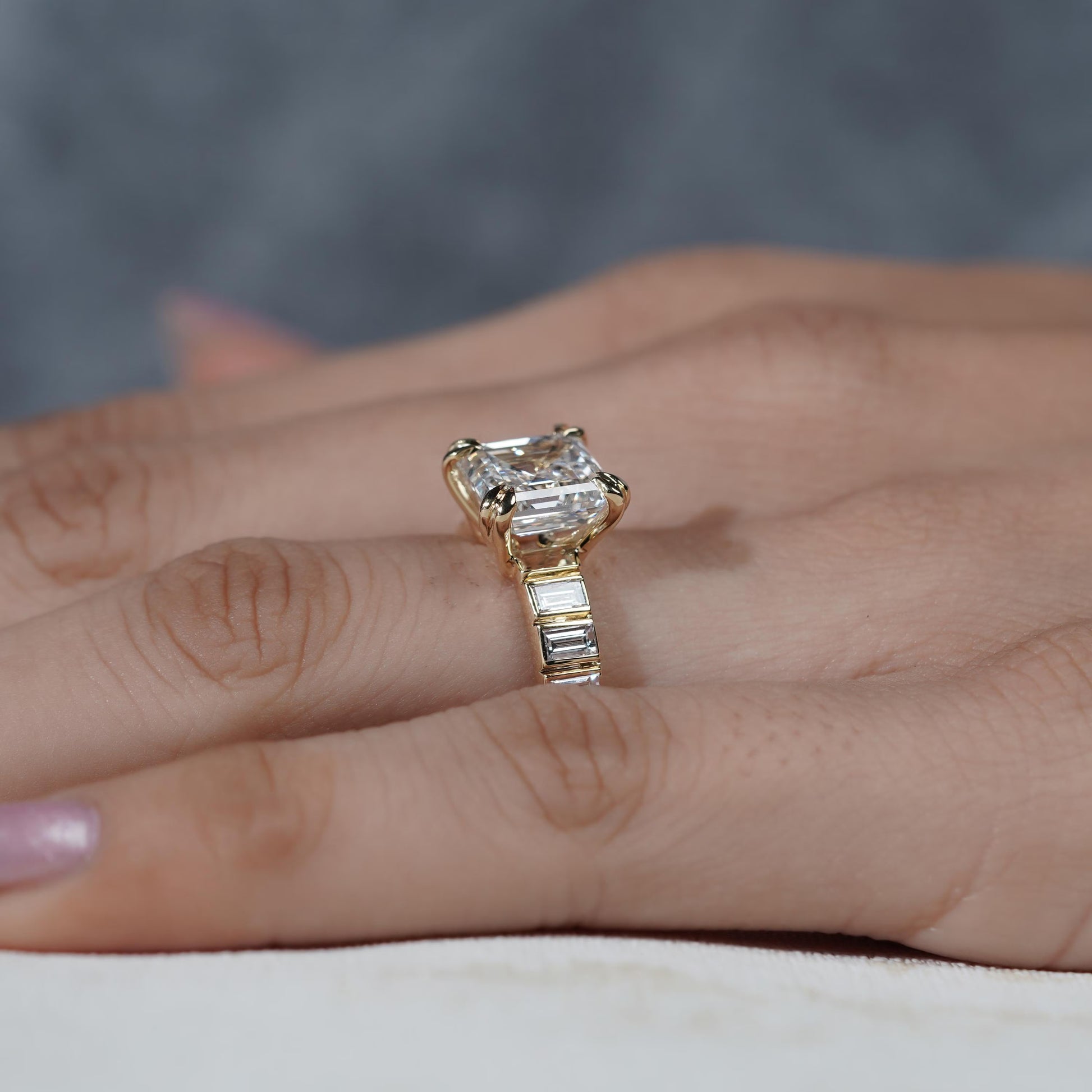Gold ring with a large diamond on a person's finger against a blurred background


