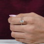 Close-up of a hand wearing a diamond ring with a blurred background

