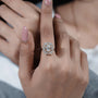 Close-up of a hand wearing a diamond ring with a blurred background
