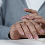 Close-up of a hand wearing a diamond ring with a blurred background