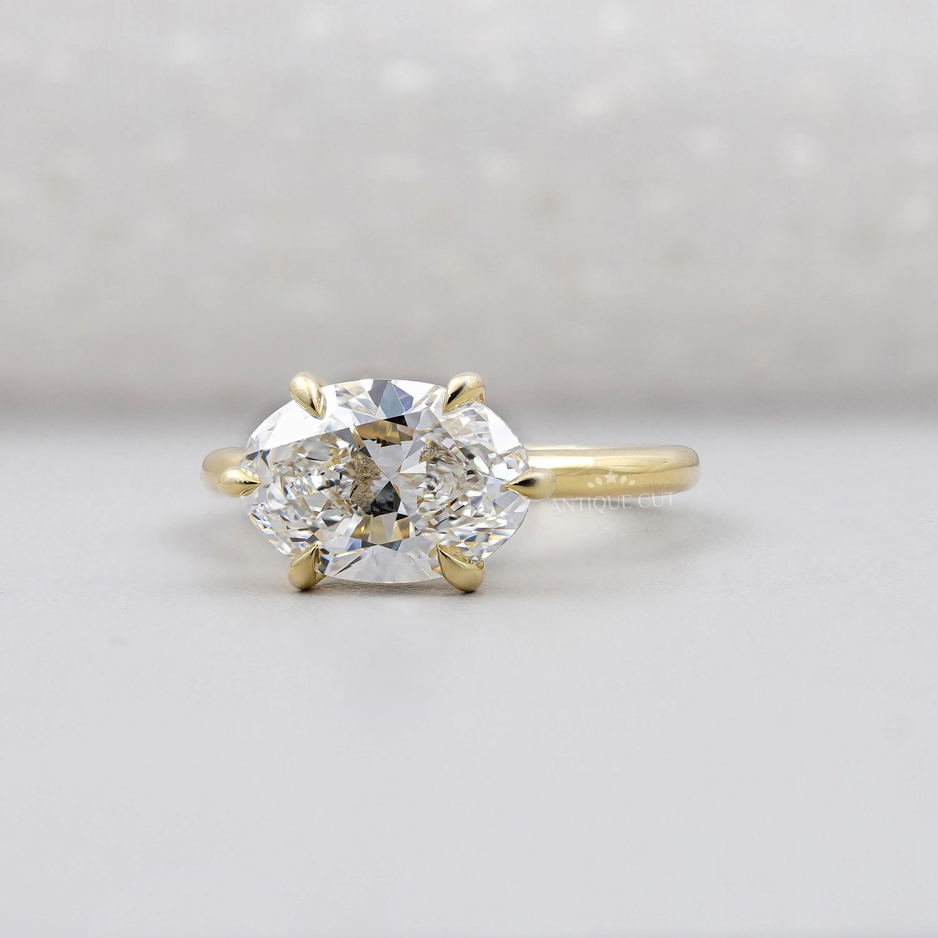 Gold ring with a large diamond on a light gray background

