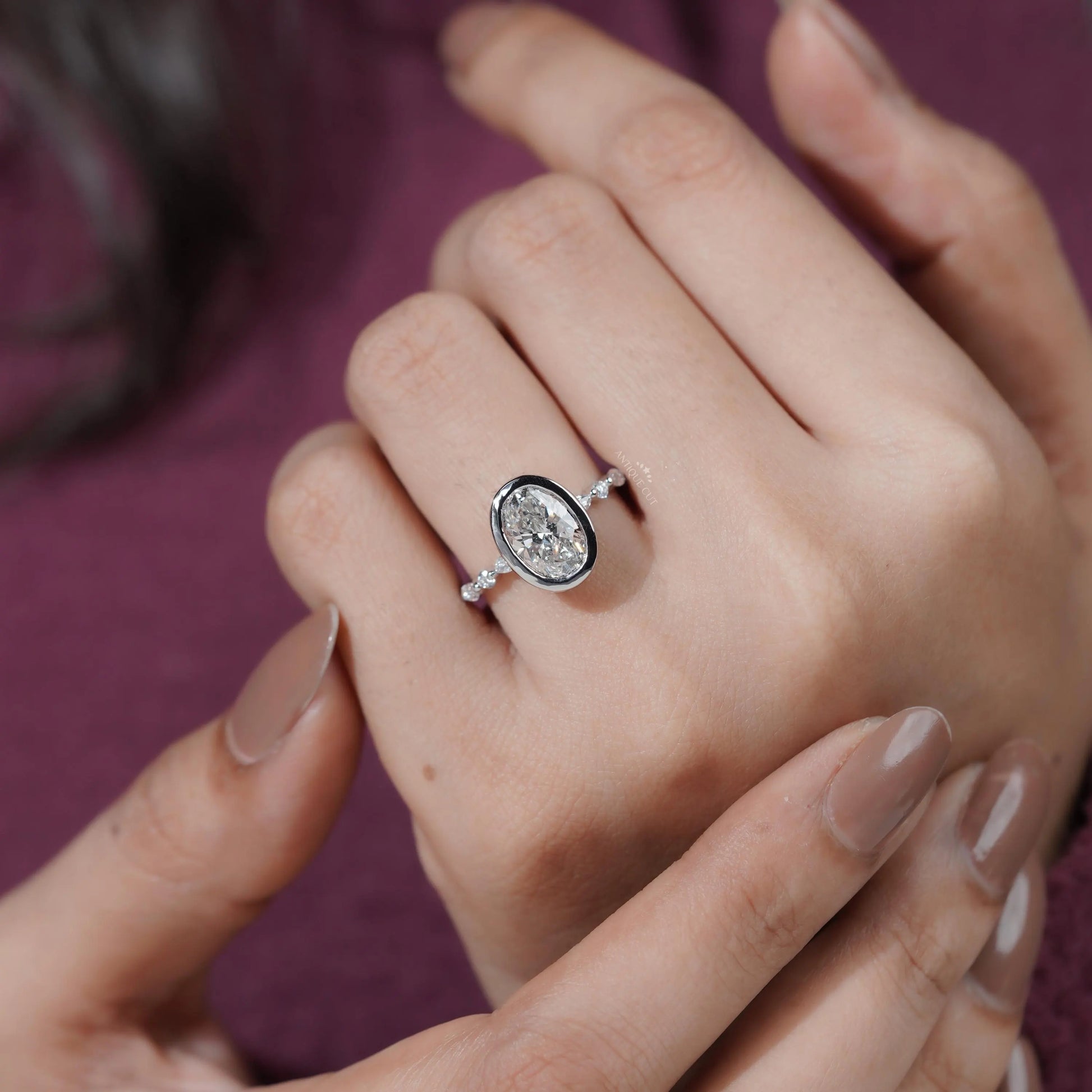Close-up of a hand wearing a diamond ring with a blurred purple background

