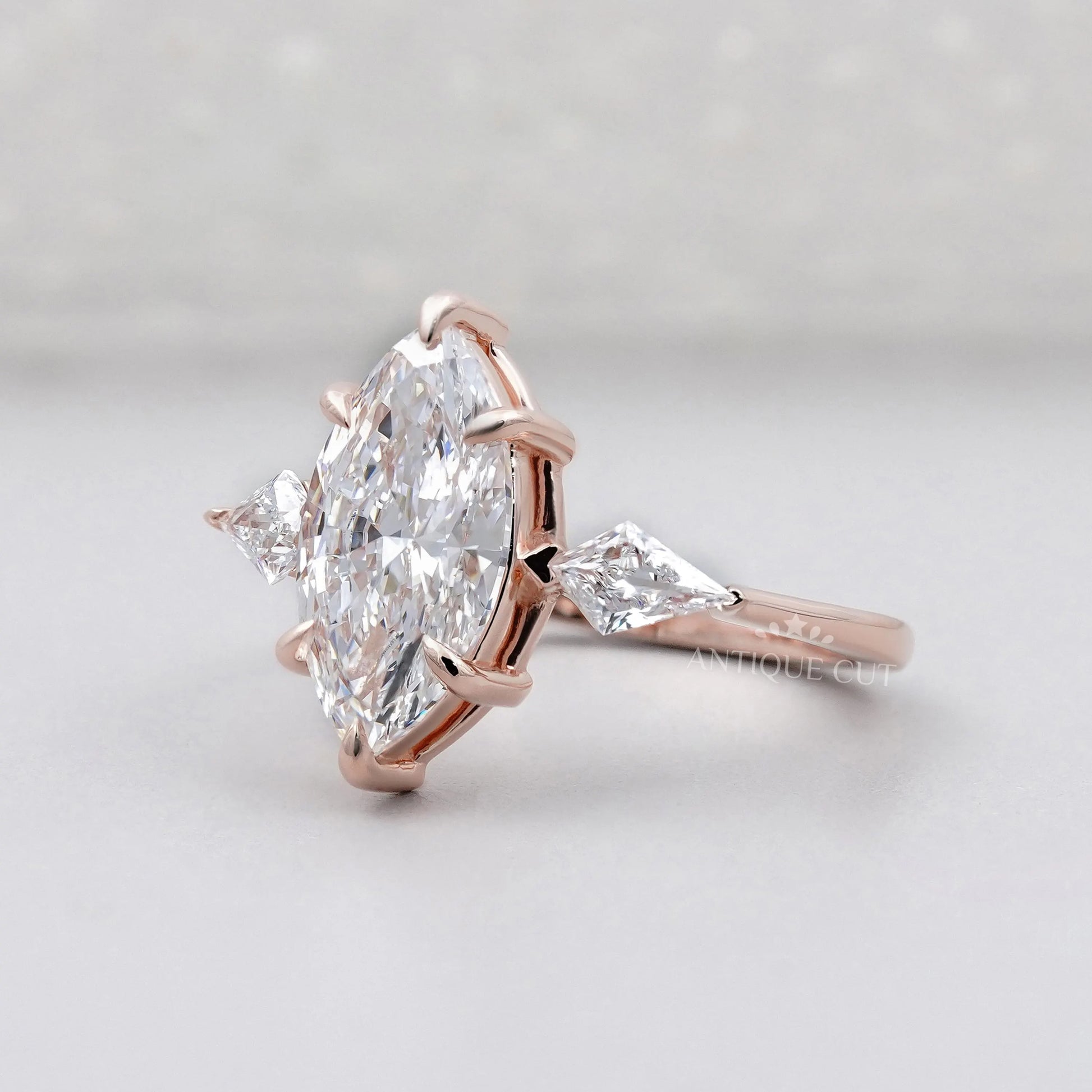 Rose gold ring with a large marquise-shaped diamond on a light gray background

