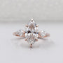 Rose gold ring with pear-shaped diamonds on a light gray background

