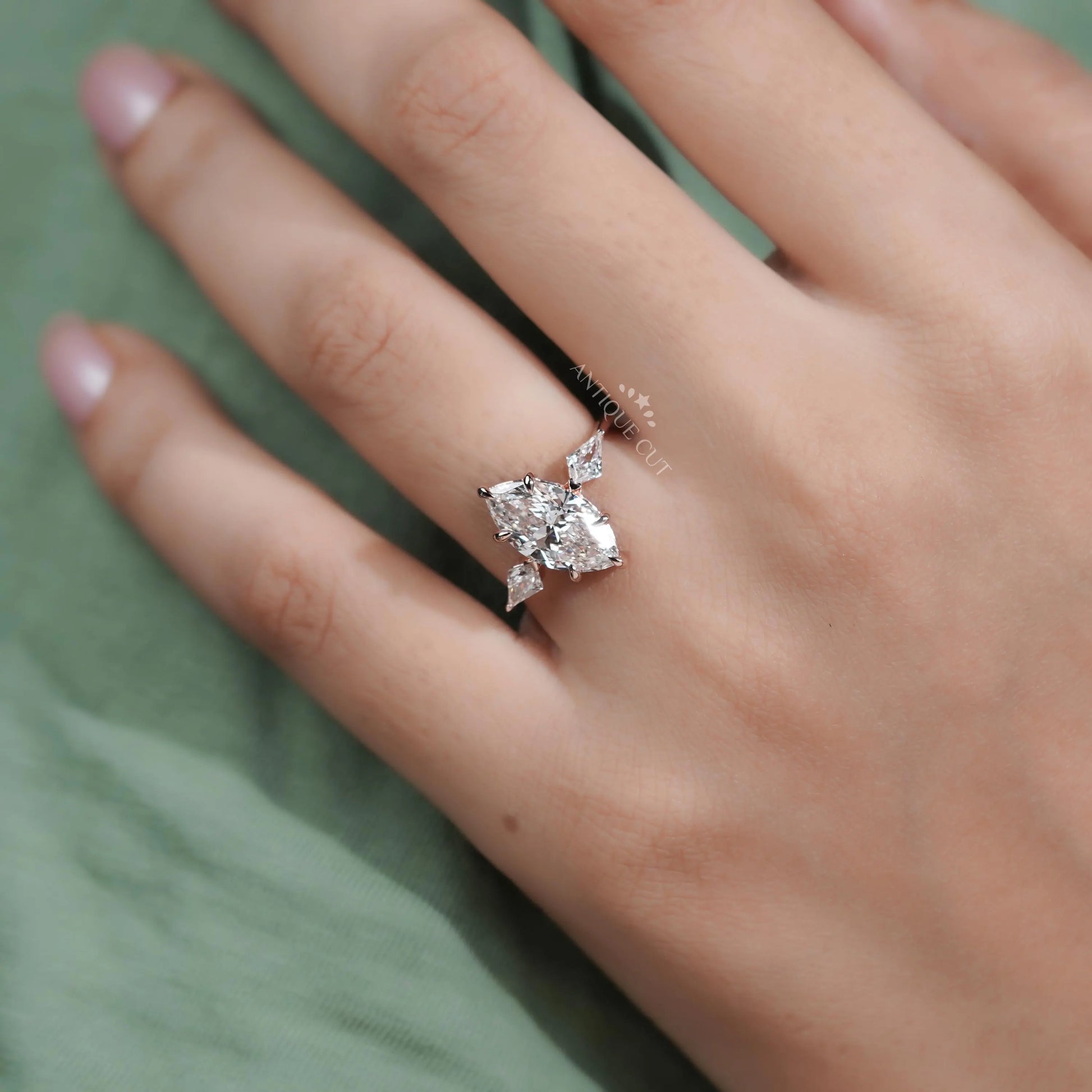 Close-up of a hand wearing a diamond ring on a green fabric background


