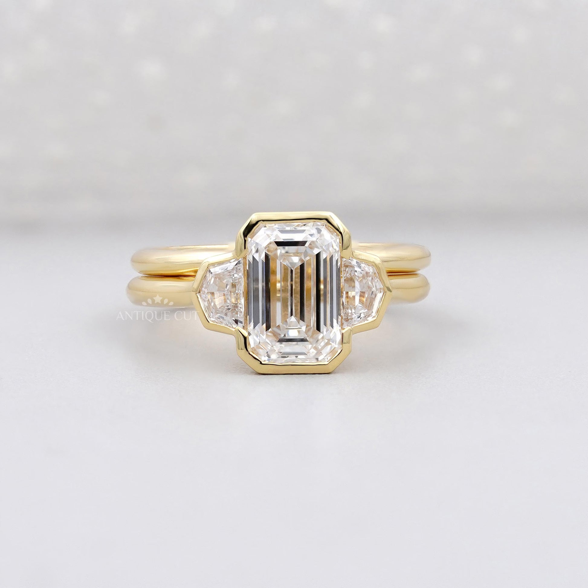 Gold ring with a large central diamond and smaller diamonds on a light gray background

