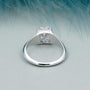 Silver ring with a diamond on a light blue feather background