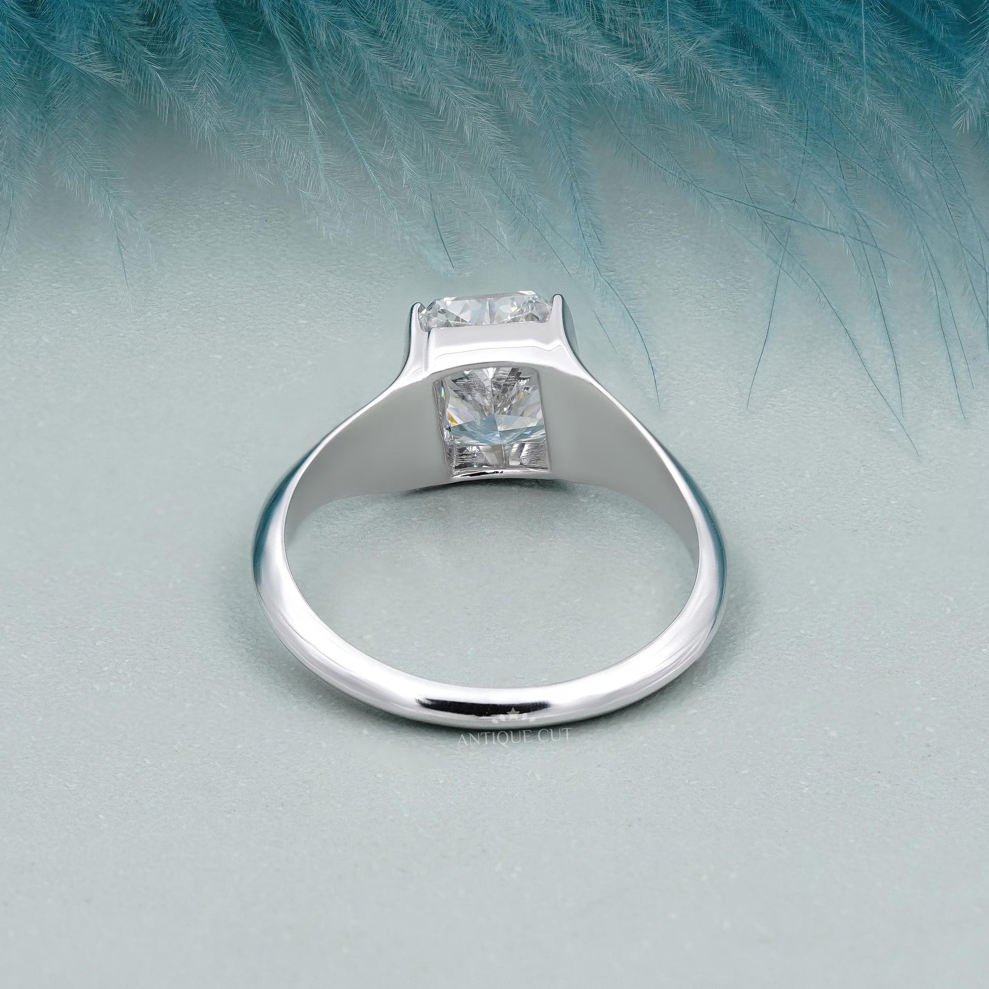 Silver ring with a diamond on a light blue feather background