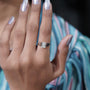 Close-up of a hand wearing a diamond ring with a blurred background

