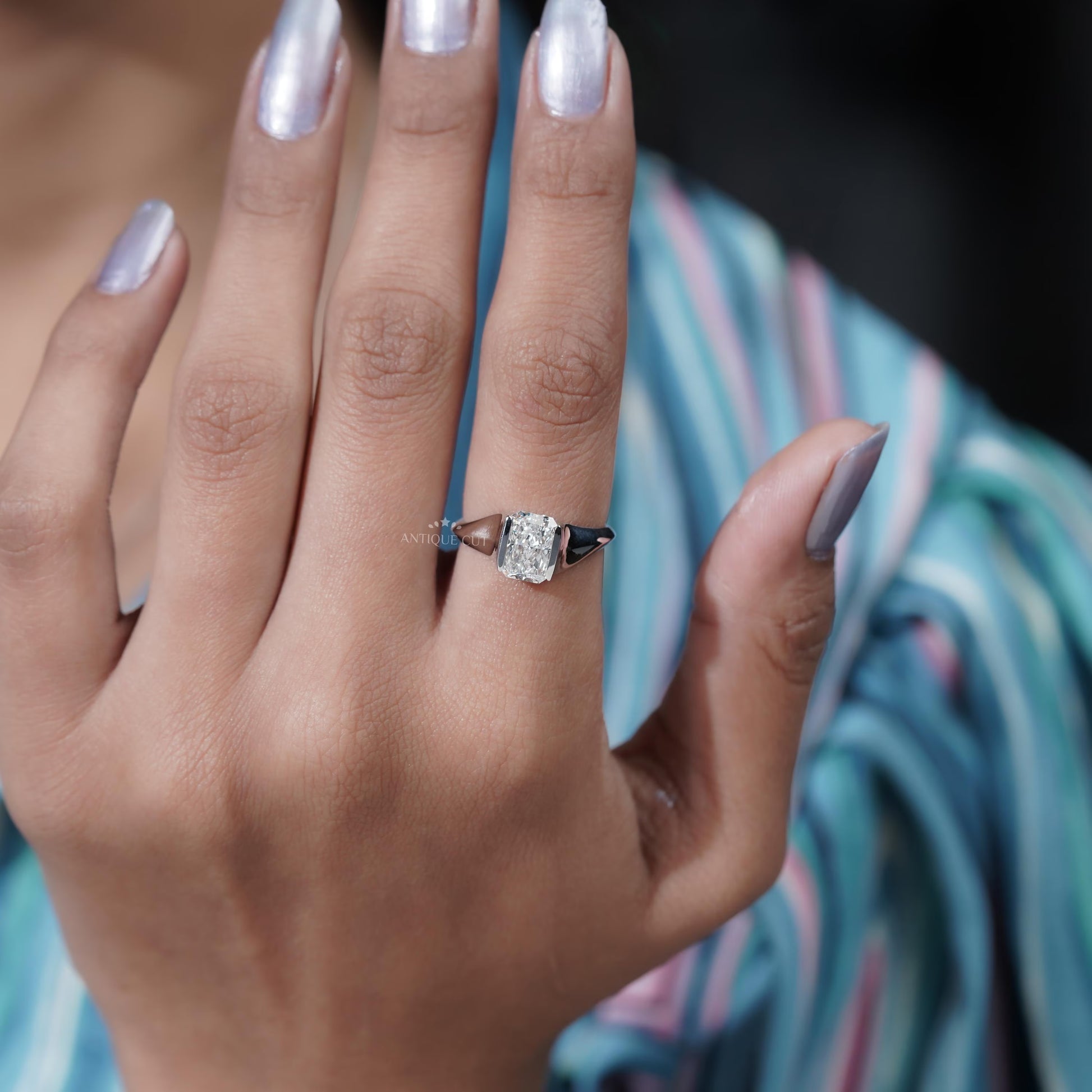 Close-up of a hand wearing a diamond ring with a blurred background

