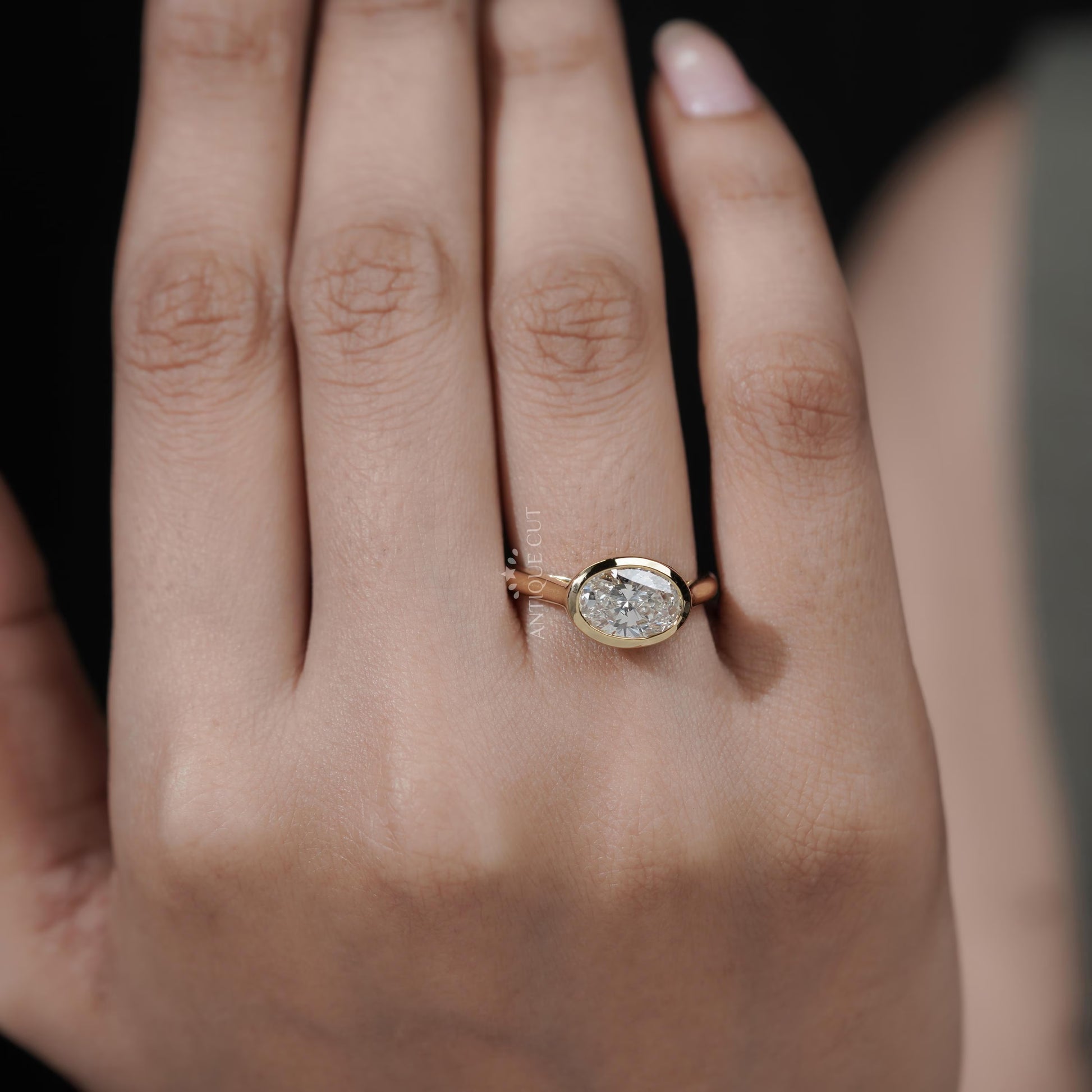 Gold ring with a diamond on a person's finger against a blurred background