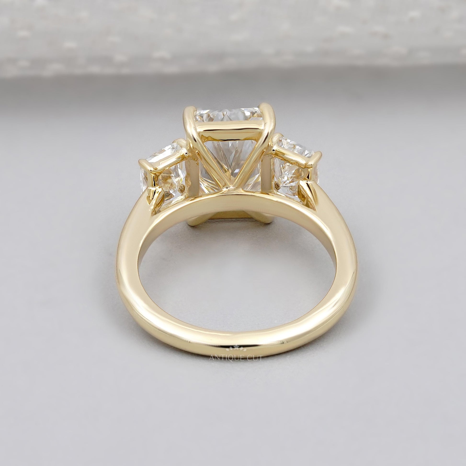 Gold ring with three diamond stones on a gray background

