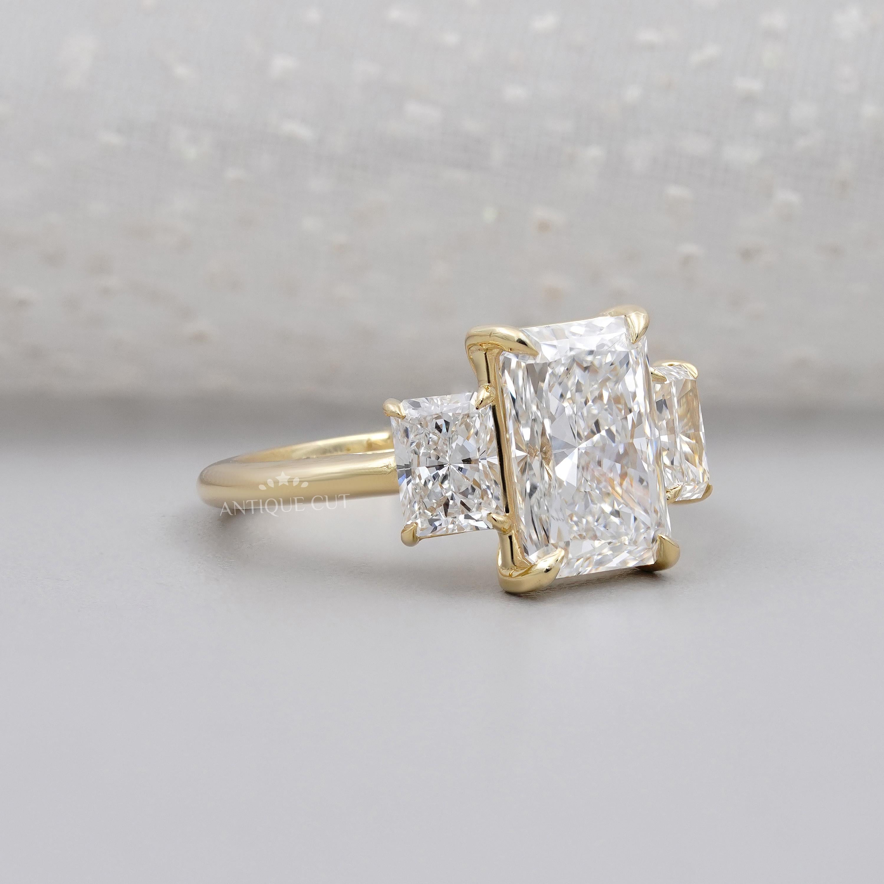 Gold ring with three diamond stones on a light gray background

