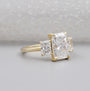 Gold ring with three diamond stones on a light gray background

