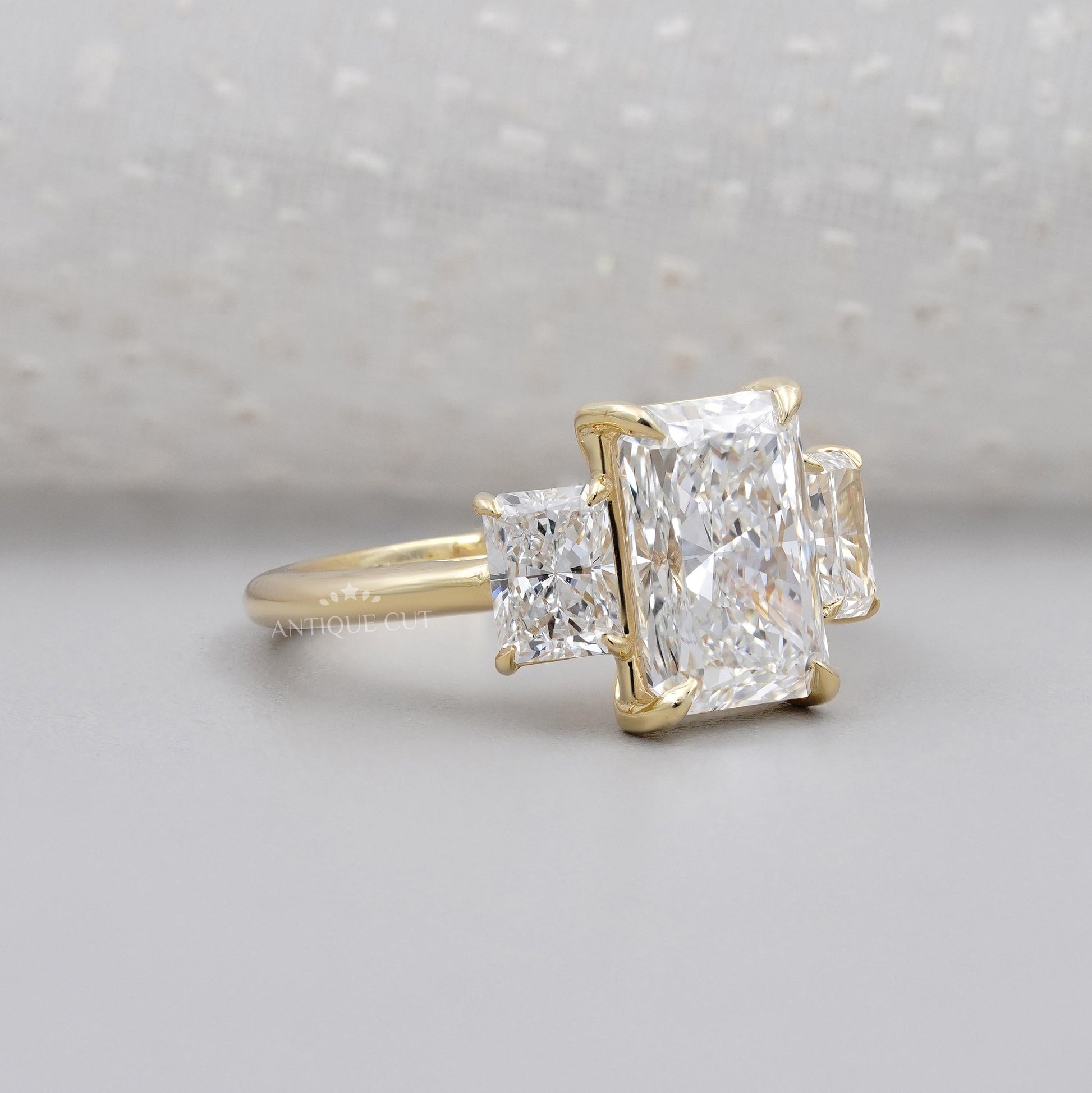 Gold ring with three diamond stones on a light gray background

