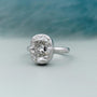 Diamond ring with a cushion-cut diamond on a light gray background

