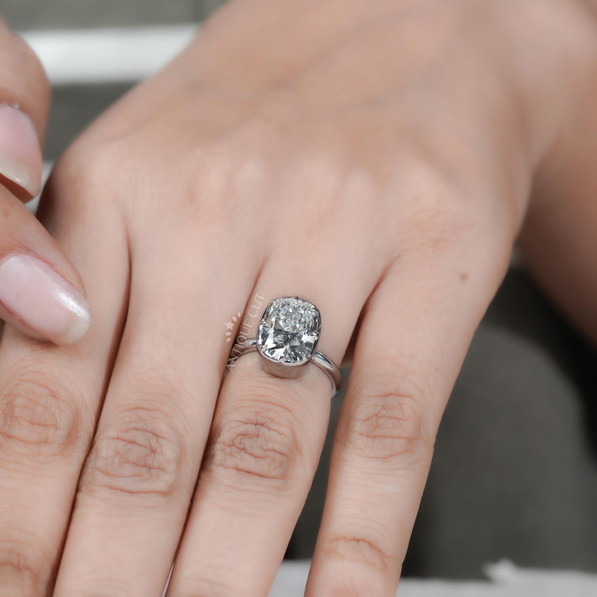 Close-up of a hand wearing a diamond ring with a blurred background


