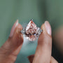 Diamond ring held between fingers with a blurred green background

